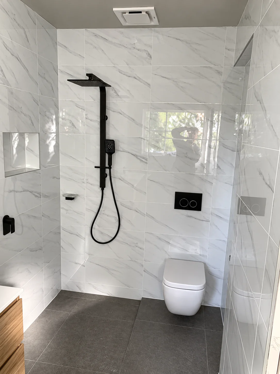 Bathroom shower with glass enclosure, tiled walls and wall-mounted fixtures.