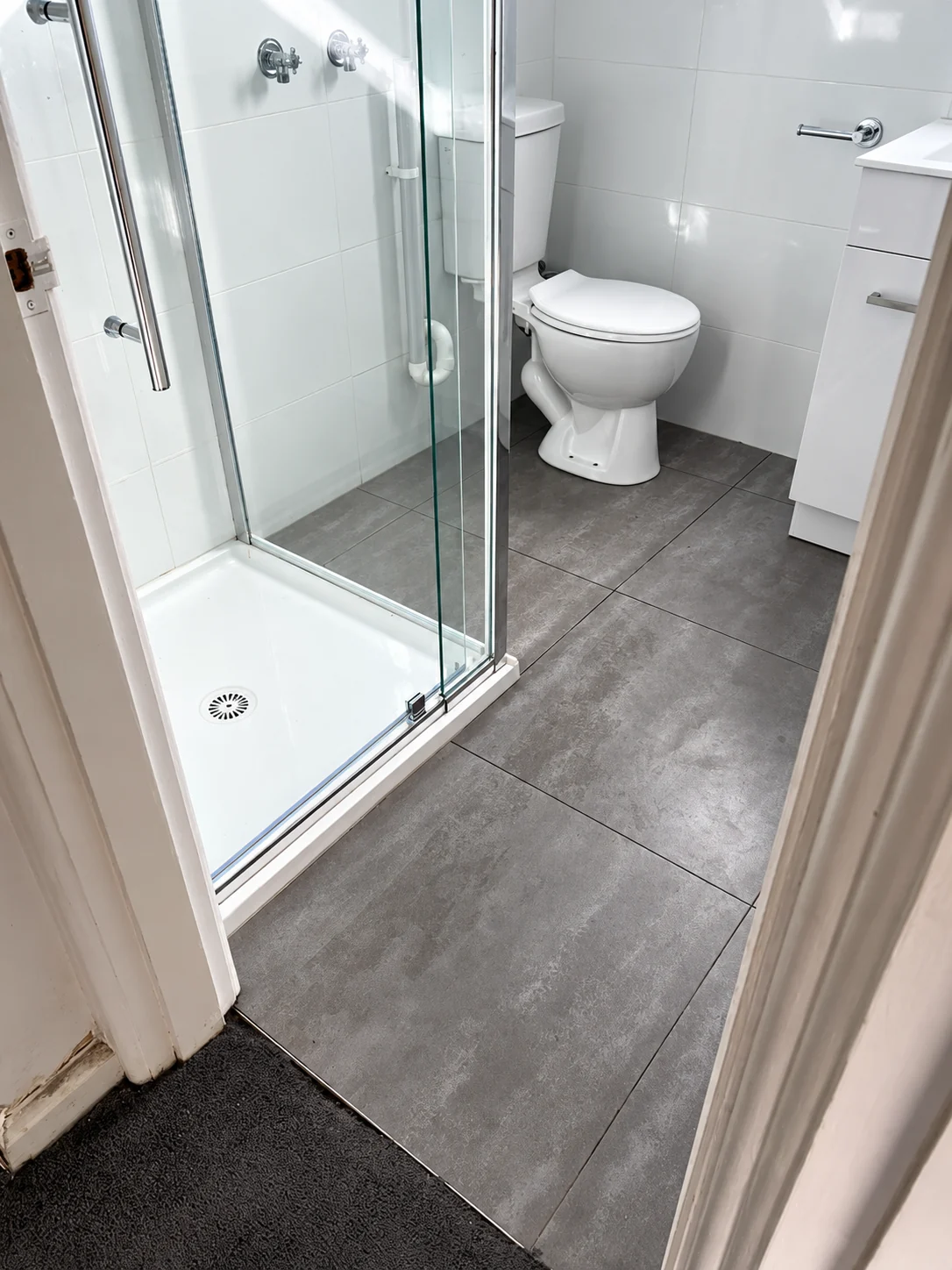 Compact bathroom with shower enclosure and toilet.